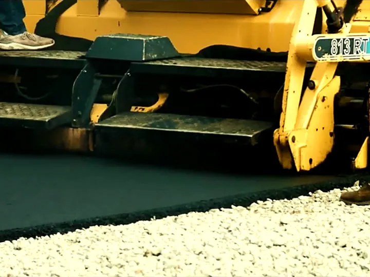 Paver screed laying a smooth black asphalt mat over a stone base
